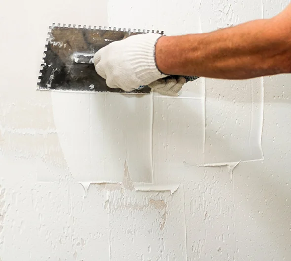 Close-up of a hand applying joint compound to a drywall seam, demonstrating finishing and smoothing during drywall repair.