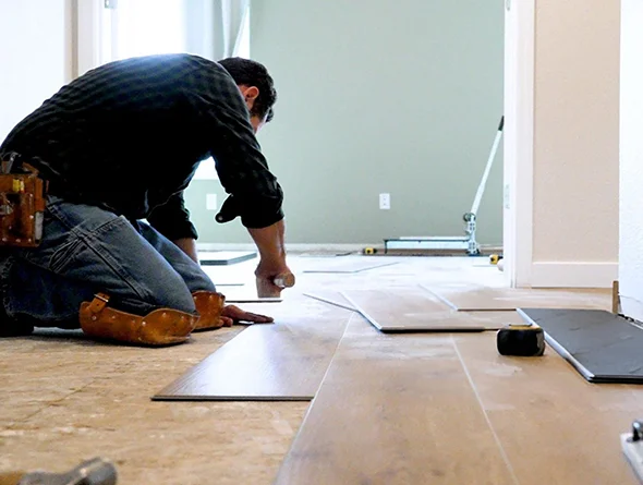 Two workers preparing a floor for hardwood installation by leveling the surface, emphasizing attention to detail in flooring installation projects.