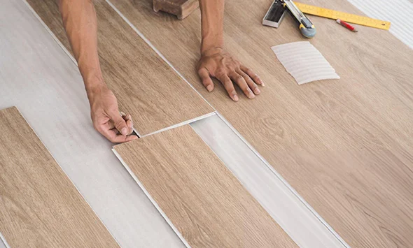 Close-up of a worker cutting flooring planks for installation, illustrating affordable flooring services.