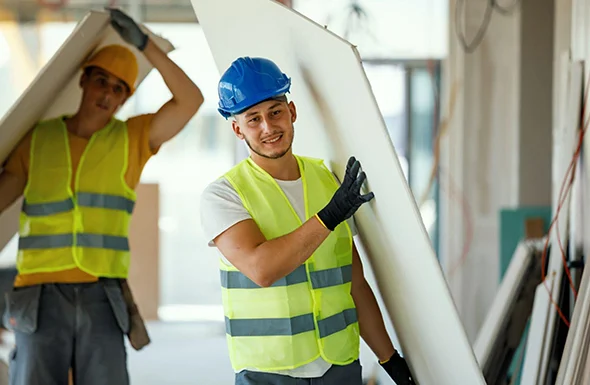 Two construction workers in safety gear inspecting drywall installation, representing professional remodeling services.