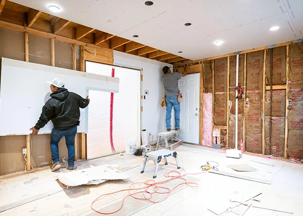Room under renovation with exposed wooden framing, tools, and drywall materials, illustrating ongoing drywall repair and installation work.