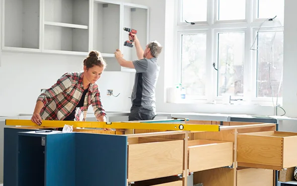 Construction worker renovating a modern kitchen with new custom cabinets, highlighting specialized kitchen remodeling services.